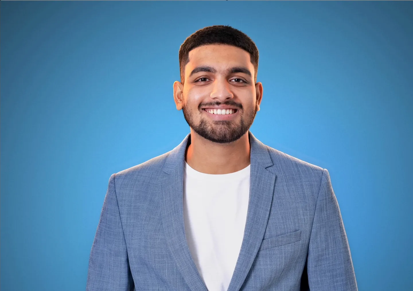 A portrait with two warm rim lights outlining the man's hair and shoulders against a blue backdrop