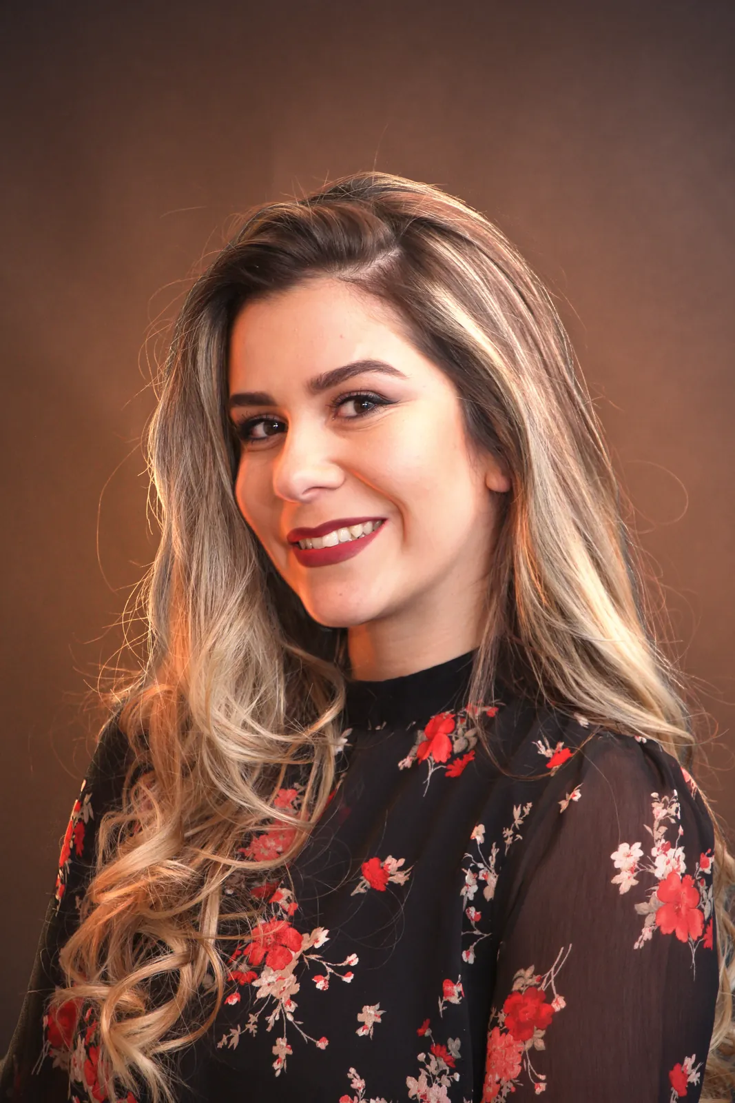 A studio portrait of a woman in a black floral blouse, the original photo
